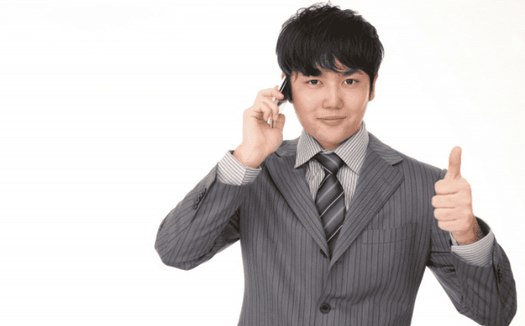 スマホで通話し親指を立てる男性