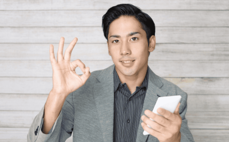 スマホを持ちOKサインをする男性