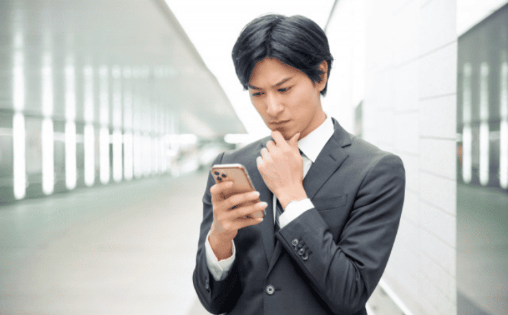 スマホを見て悩む男性