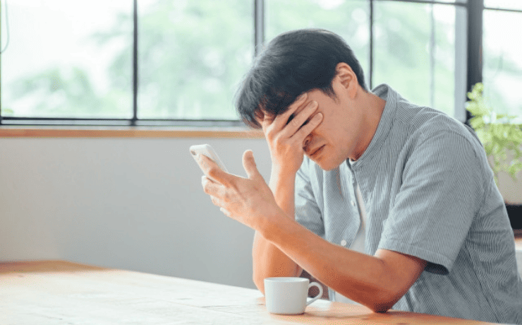 スマホを目を伏せる男性