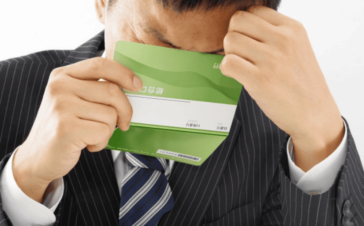 通帳を見て悩む男性