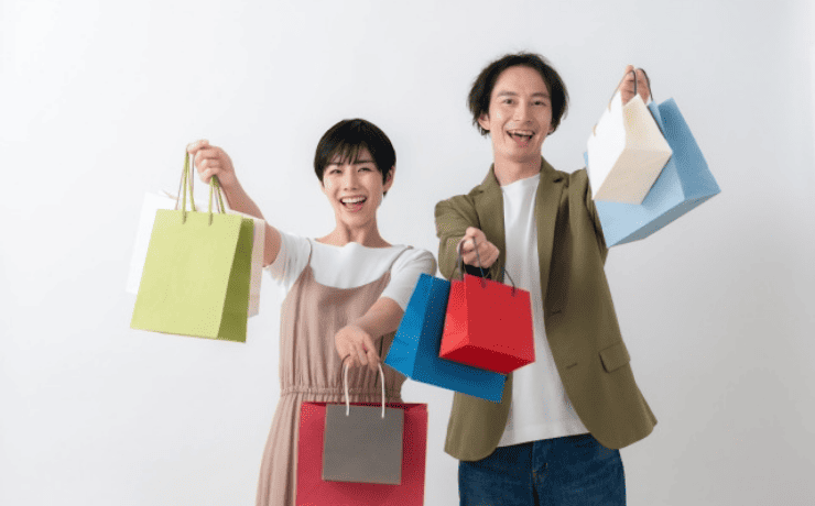 たくさんの紙袋を持ち上げる男女