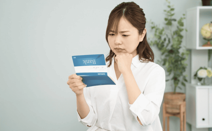 通帳を見て悩む女性