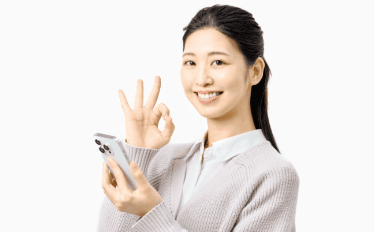 スマホを見てOKサインする女性