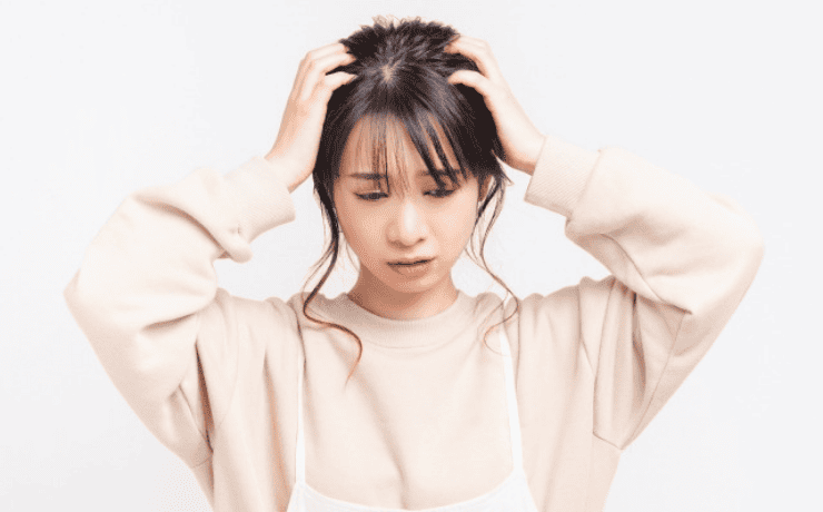 両手で頭をかかえて悩む女性