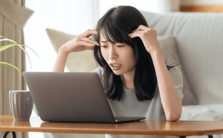 パソコンを見て頭をかかえる女性