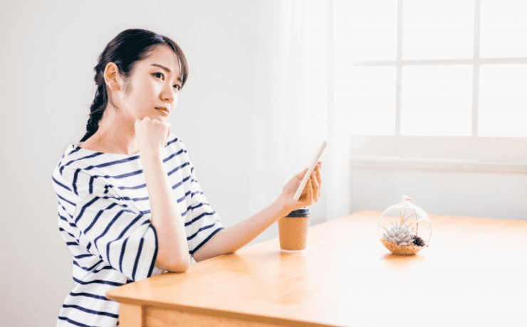 スマホを見て悩む女性