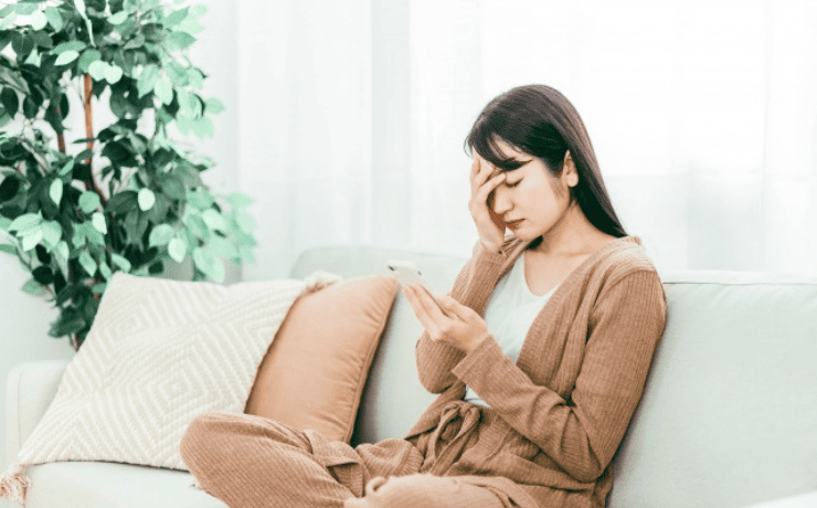 スマホを見て頭を抱える女性
