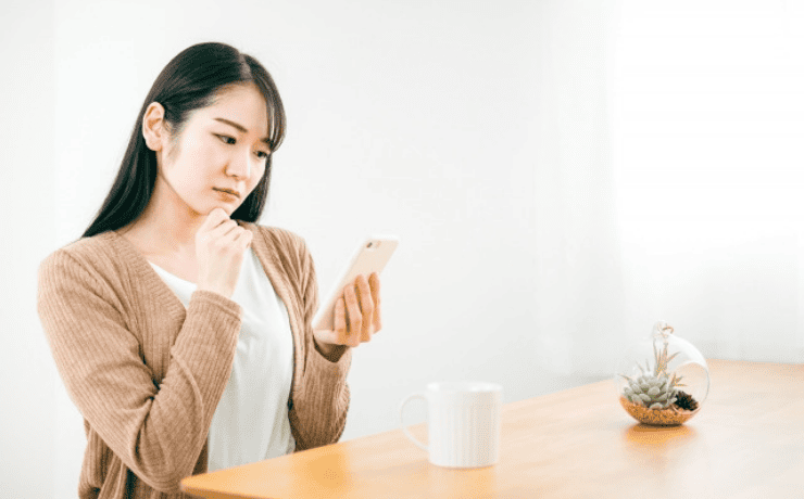 スマホを見て悩む女性