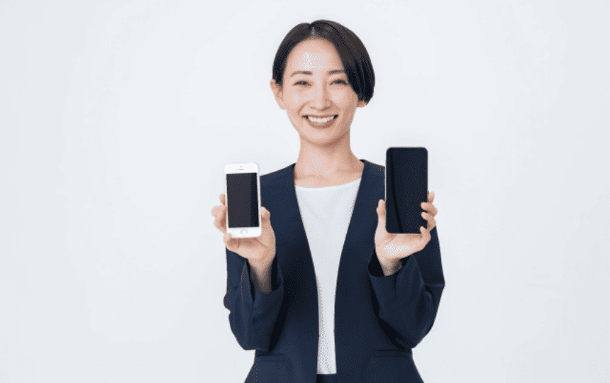 スマホを両手に持つ女性