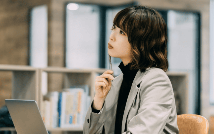 ノートパソコンの前で遠くを眺める女性