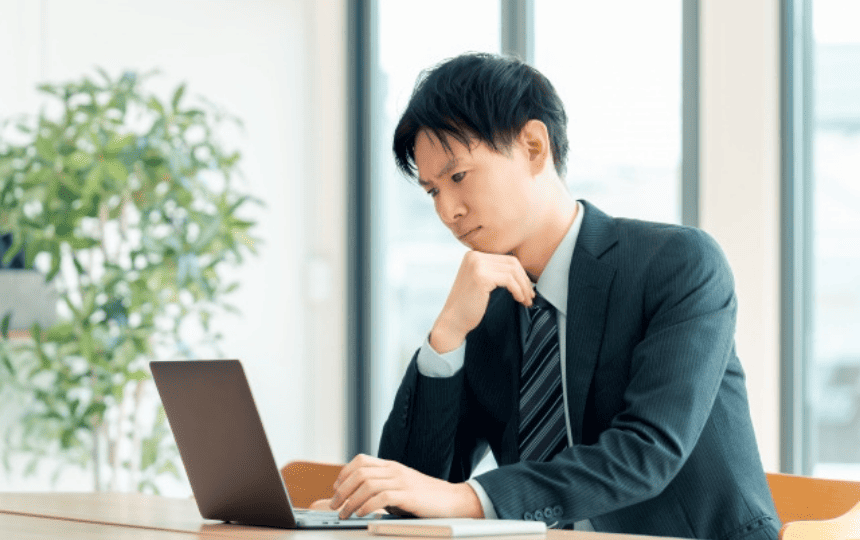 ノートパソコンを眺めるスーツ姿の男性