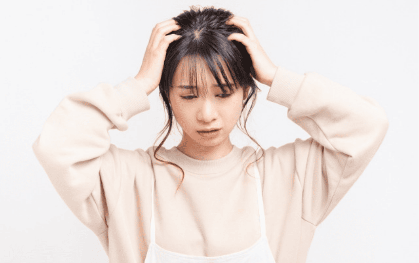 両手で頭をかかえる女性