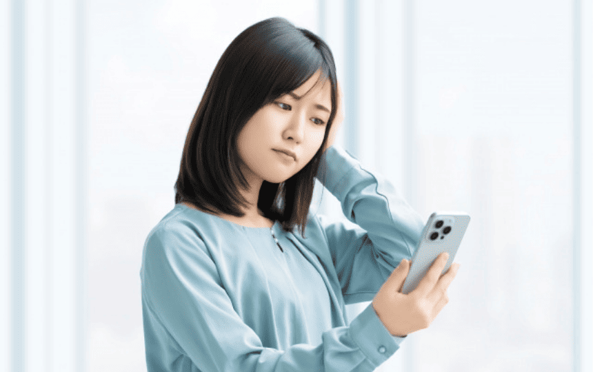 頭を抱えてスマホを見る女性