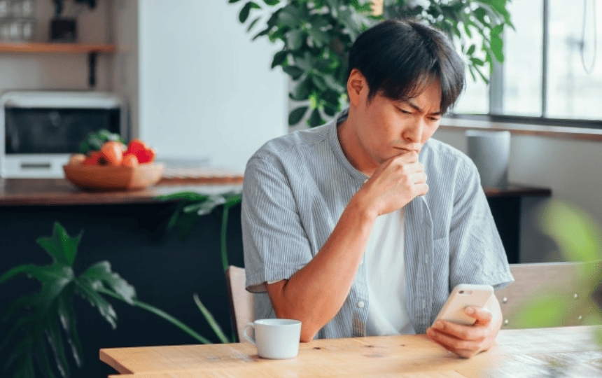 難しい顔でスマホを見る男性