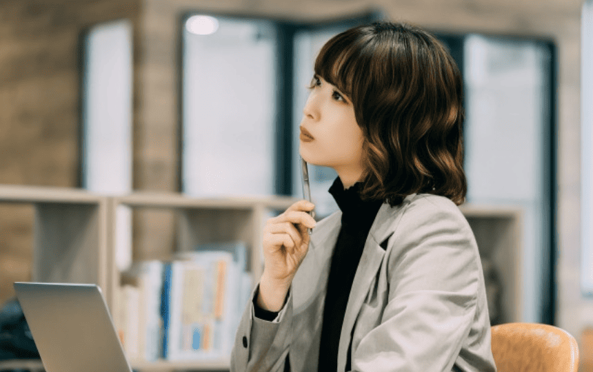 ノートパソコンを前に遠くを眺める女性