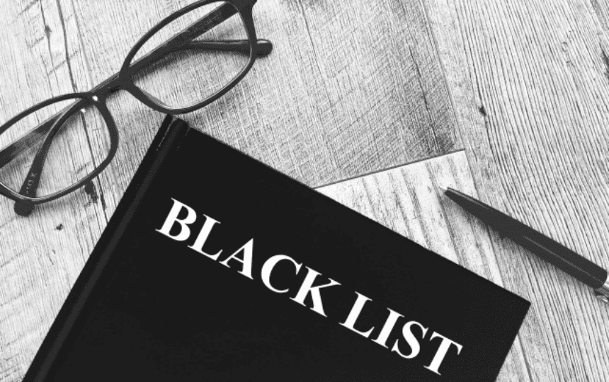 ブラックリストと書かれた本とメガネのモノクロ写真