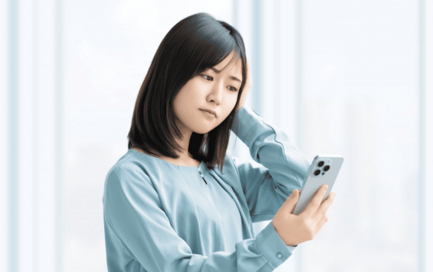 スマホ画面を見て悩む女性