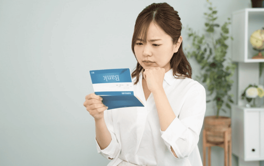 通帳を見て悩む女性