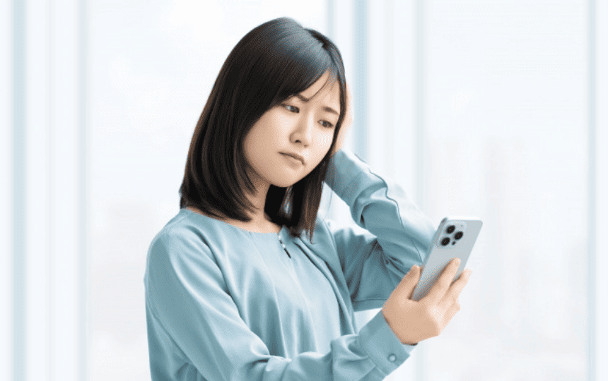 スマホを手に悩む女性