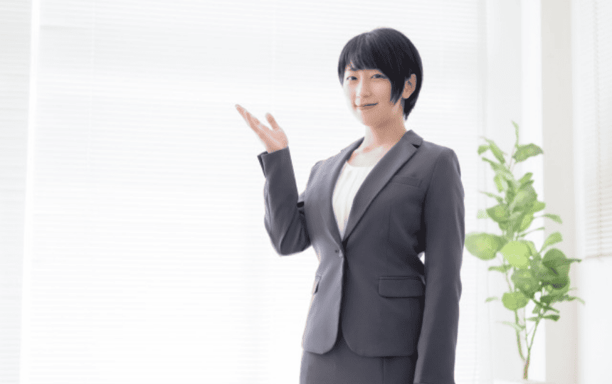 手を挙げるスーツ姿の女性