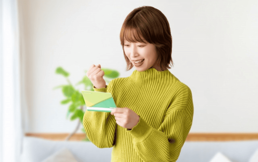 通帳を見ながらガッツポーズする女性