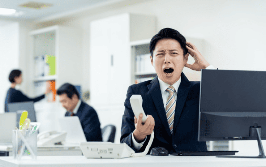 頭を抱えて受話器を握る男性