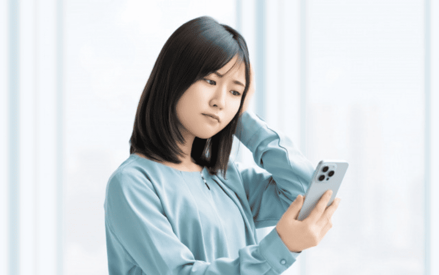 スマホを見て悩む女性