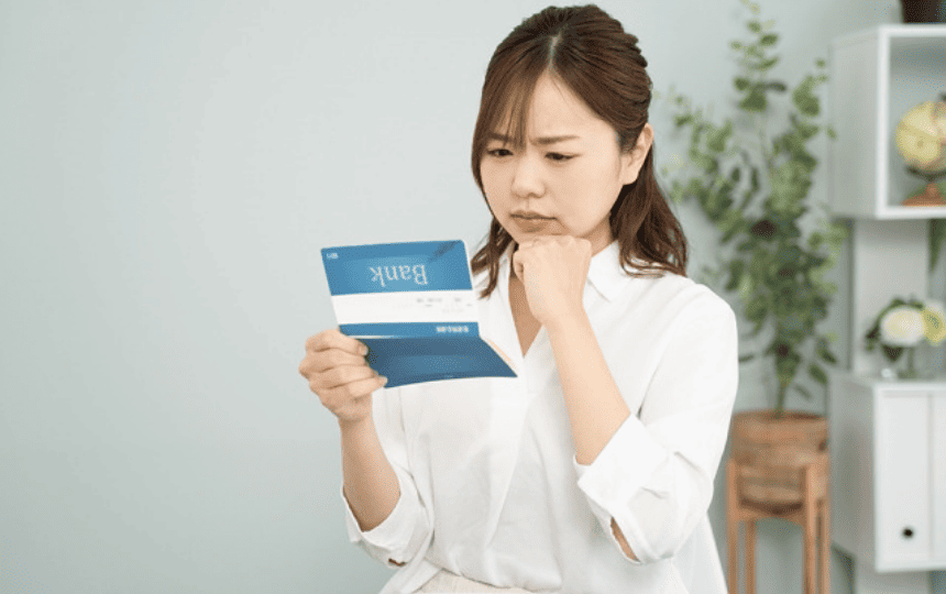 通帳を見て悩む女性