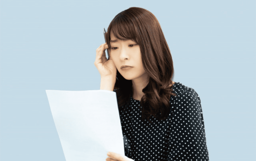 書類を見て頭をかかえる女性