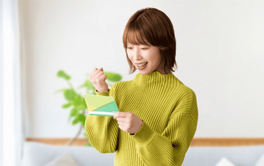 通帳を見てガッツポーズをする女性