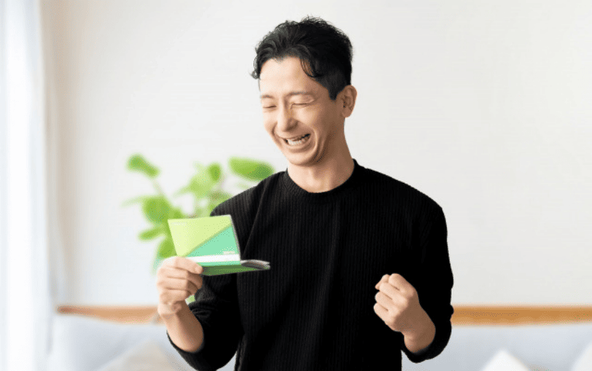 通帳を見てガッツポーズする男性