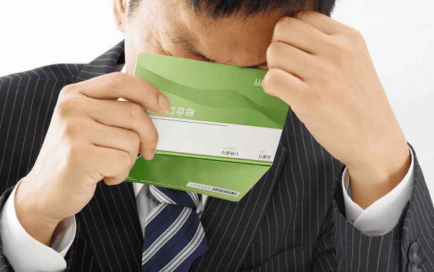 通帳を見て頭をかかえる男性